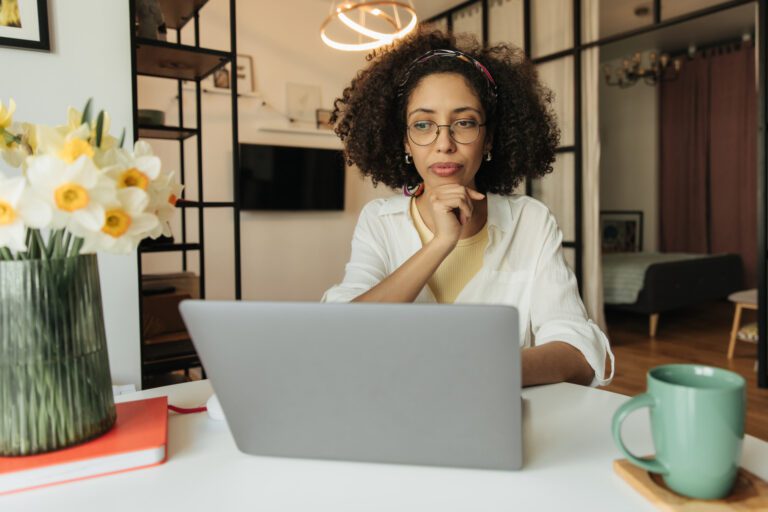 A business woman sitting in front of a computer thinking. Photo represents blogging for small business